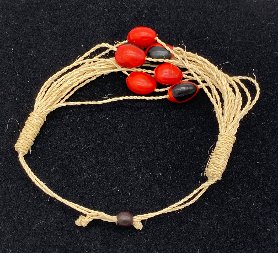 Woven strand bracelet with red and black seeds